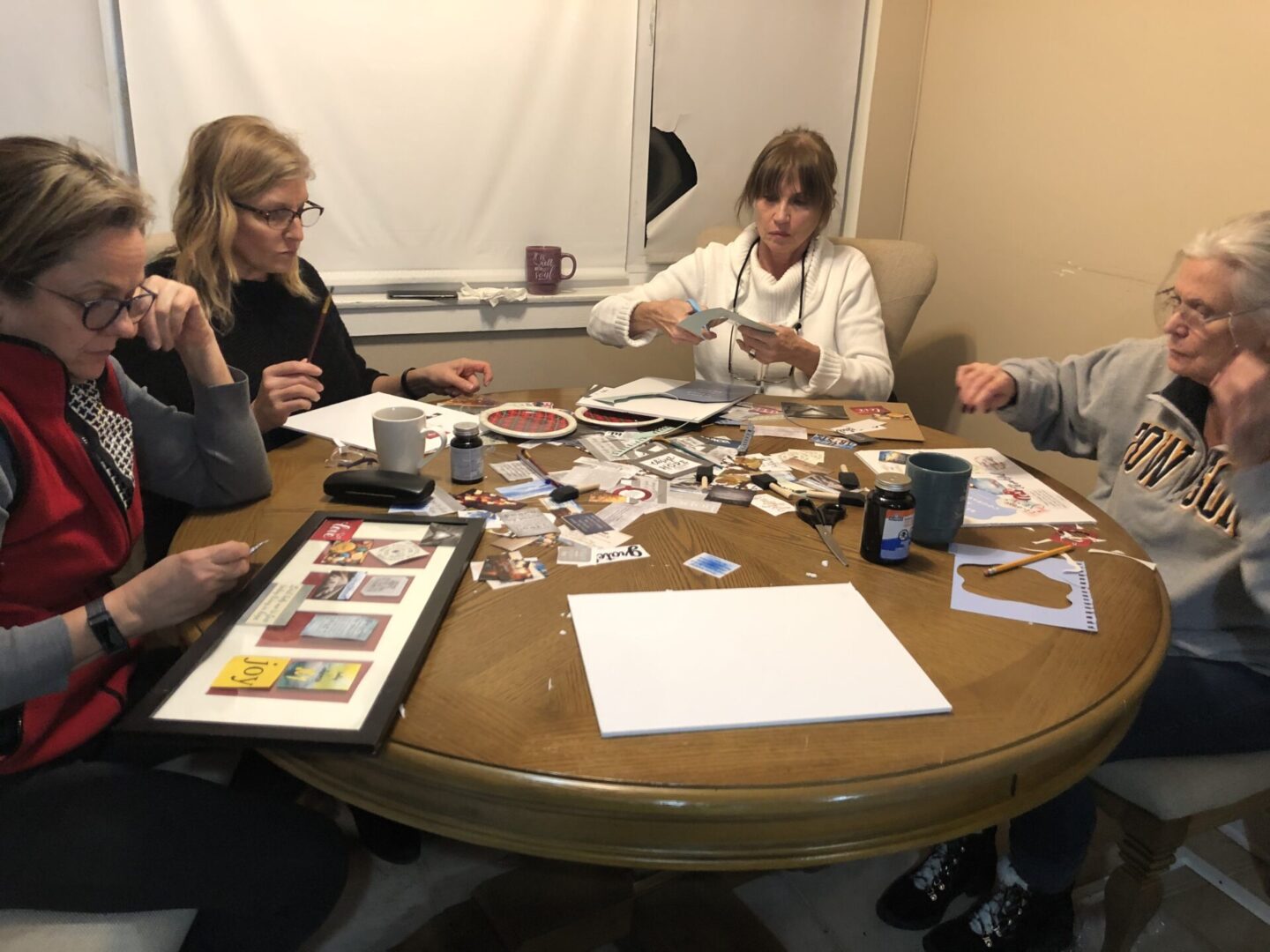 Group of old ladies playing cards on a table along with others