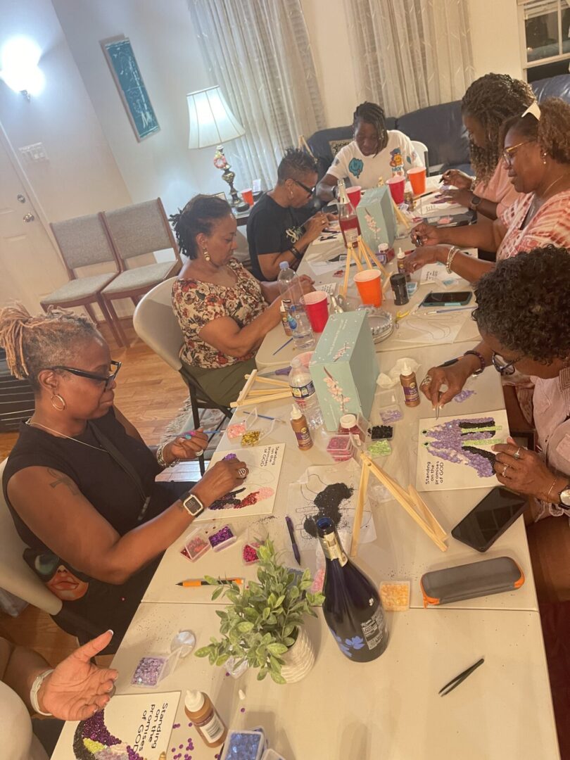 A group of people gathered around a table, engaged in a creative activity.