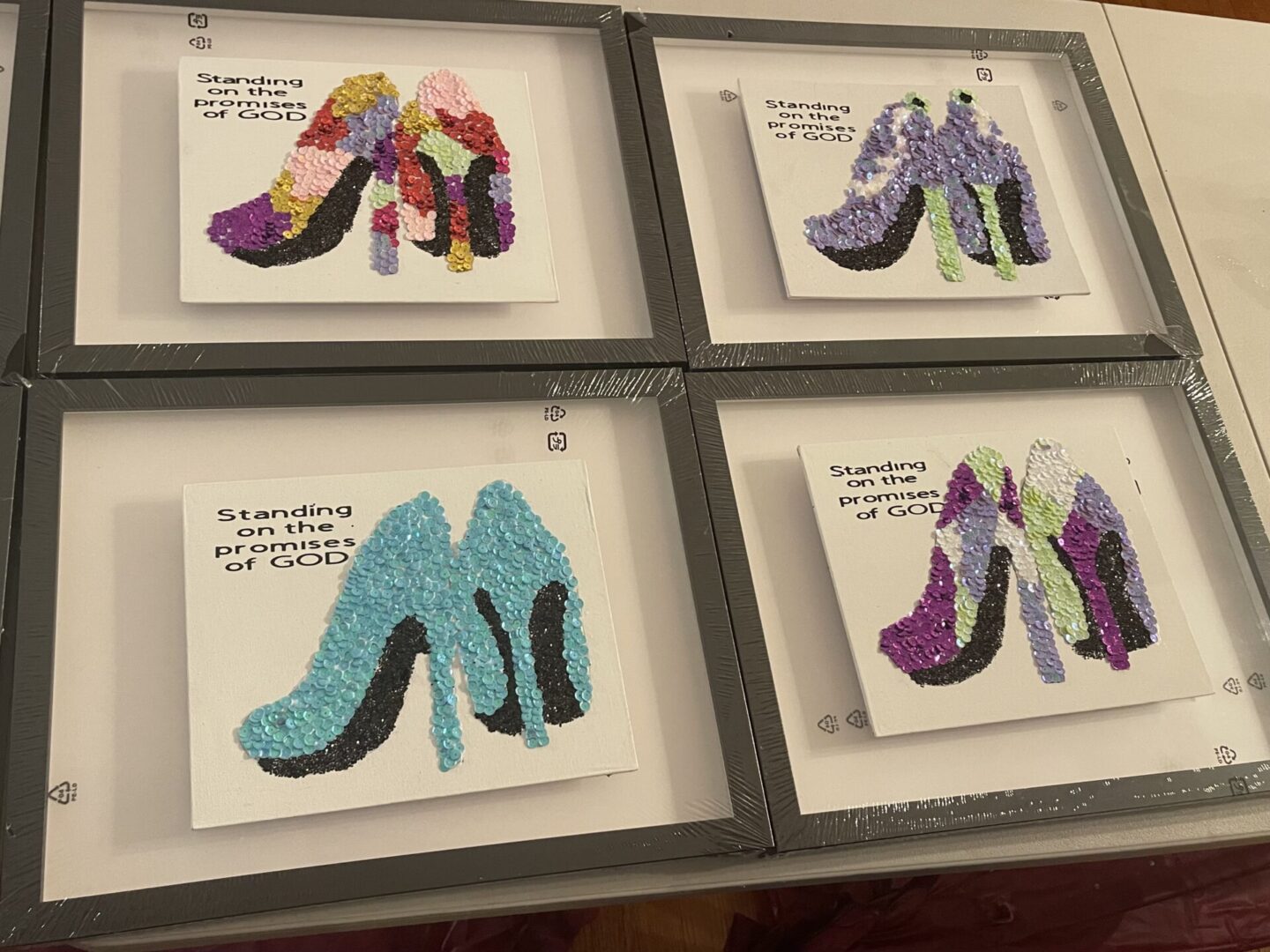 Four framed artworks of stylish high-heeled shoes in various colors and patterns.