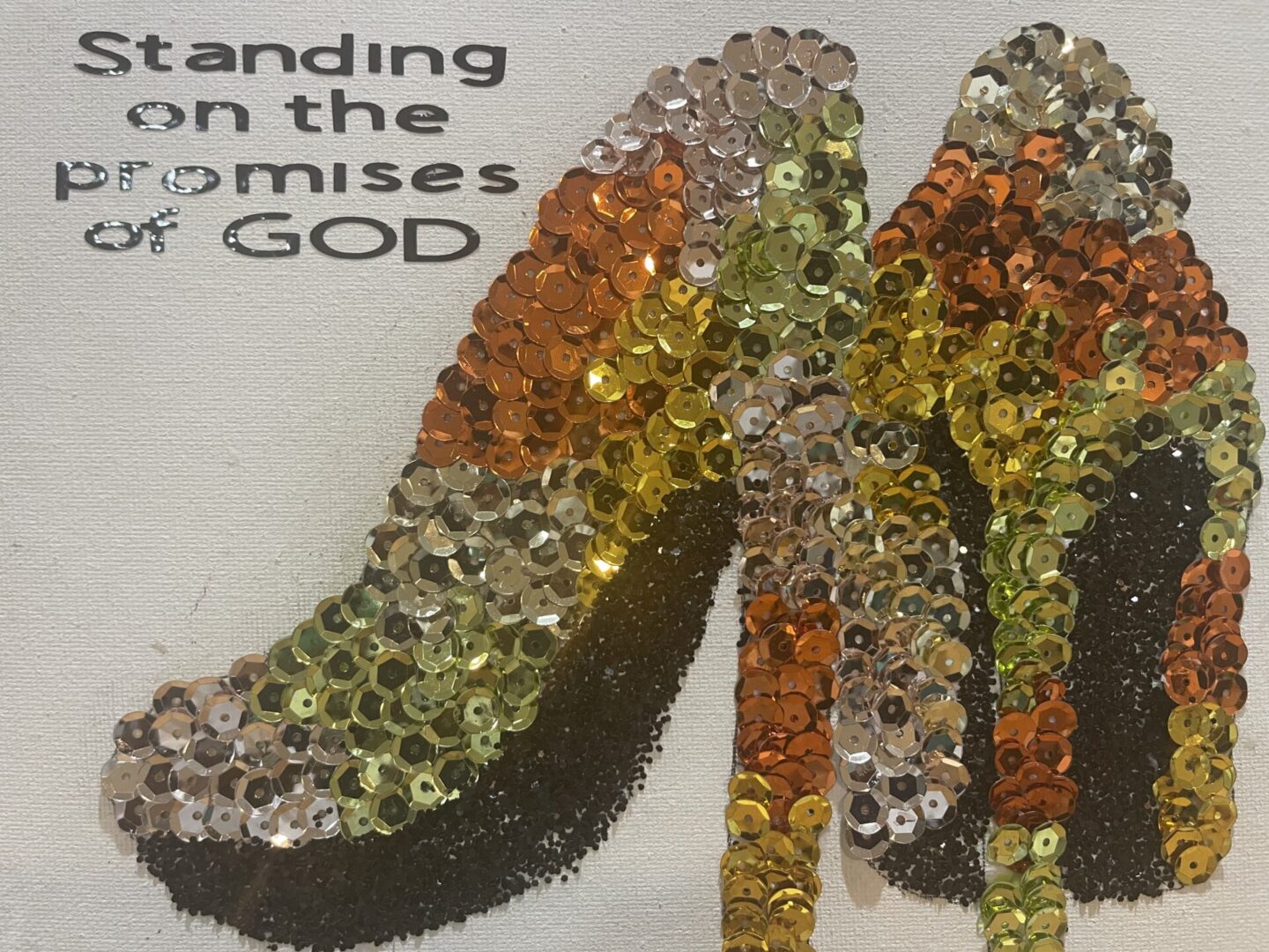 High-heeled shoes covered in colorful rhinestones with a motivational quote.
