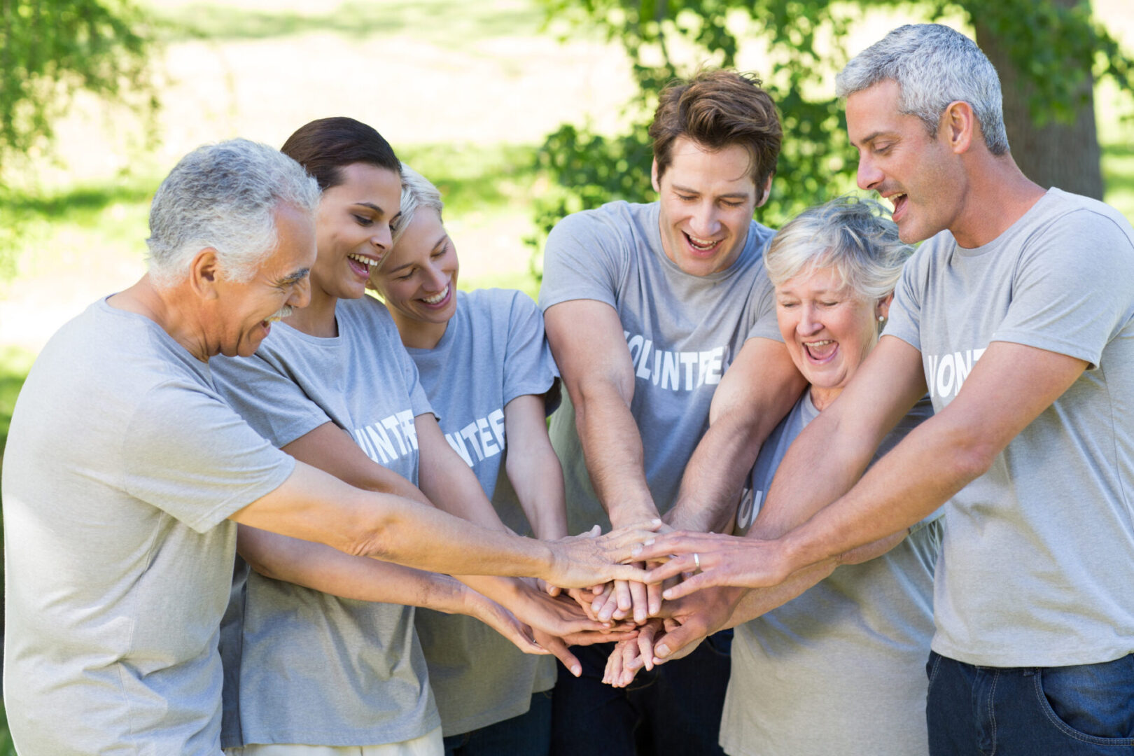 Happy volunteer family putting their hands together on a sunny day